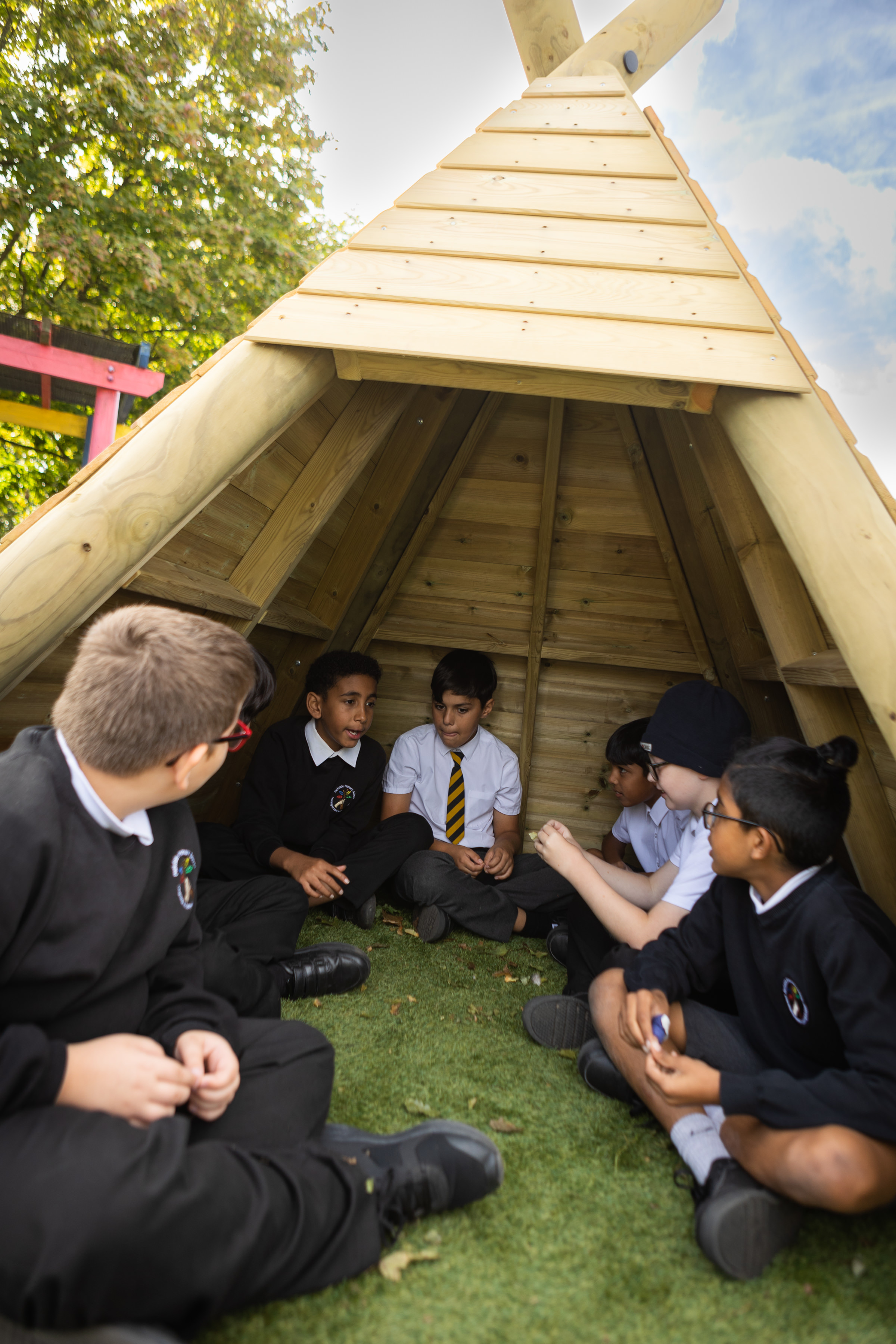 Children sitting in wooden teepee