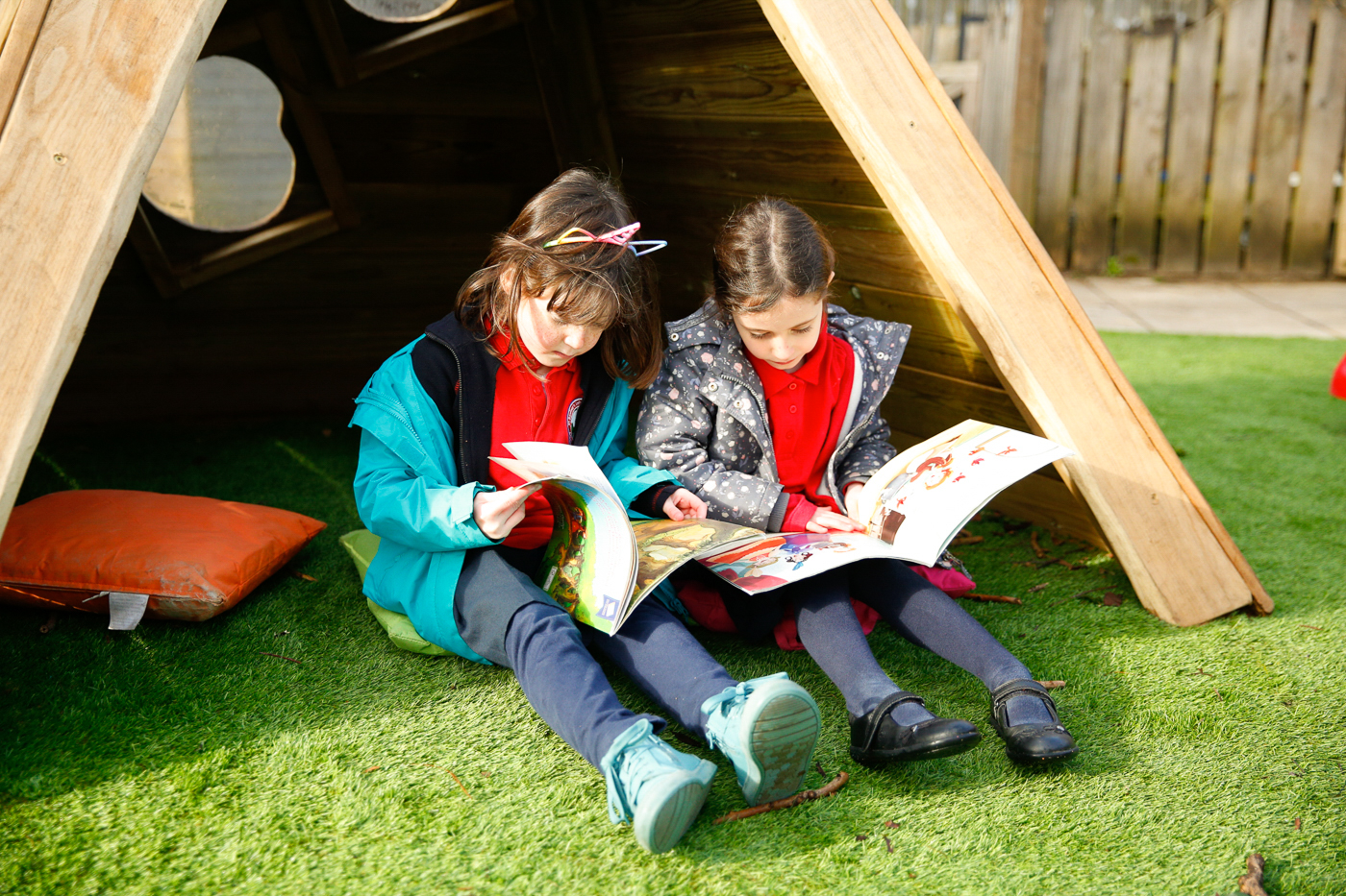 Children reading in outdoor wooden teepee